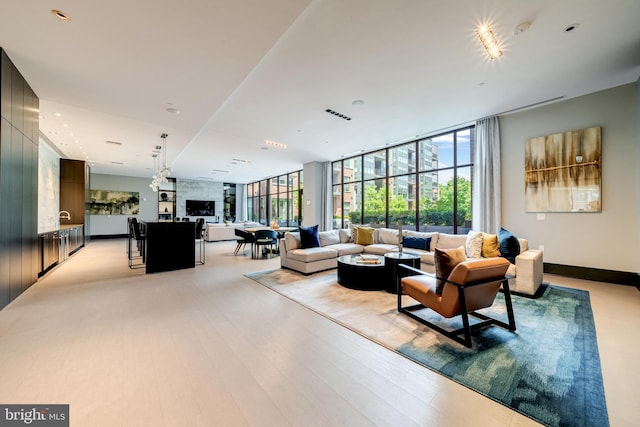 living room with expansive windows, visible vents, and light wood finished floors