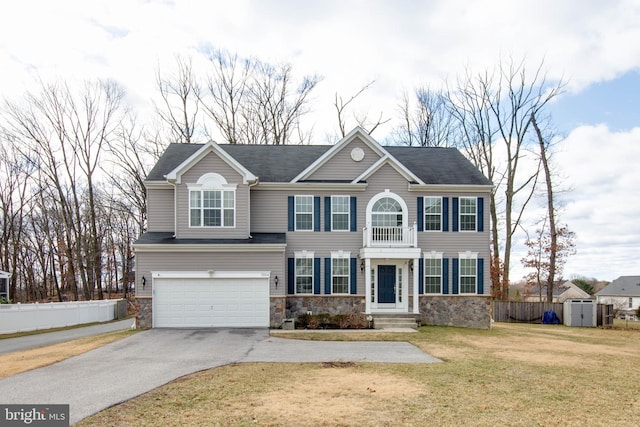 view of front facade featuring a garage, fence, driveway, stone siding, and a front yard