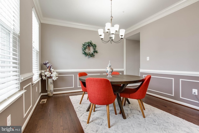 dining room with wood finished floors, a wainscoted wall, crown molding, and an inviting chandelier