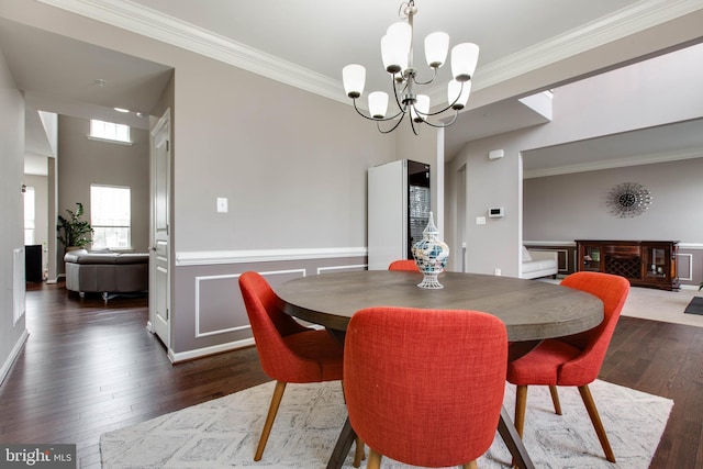 dining space featuring a chandelier, a wainscoted wall, wood-type flooring, and crown molding