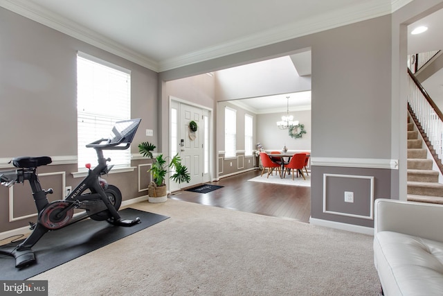 workout room featuring baseboards, ornamental molding, a chandelier, and carpet flooring