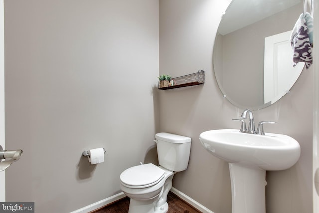 bathroom featuring baseboards, a sink, toilet, and wood finished floors