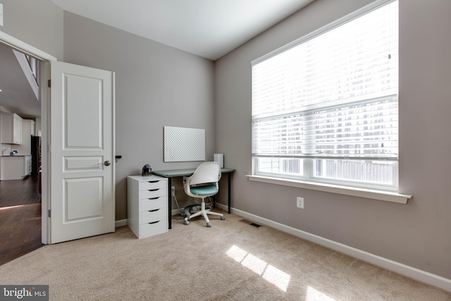 carpeted office space featuring visible vents and baseboards