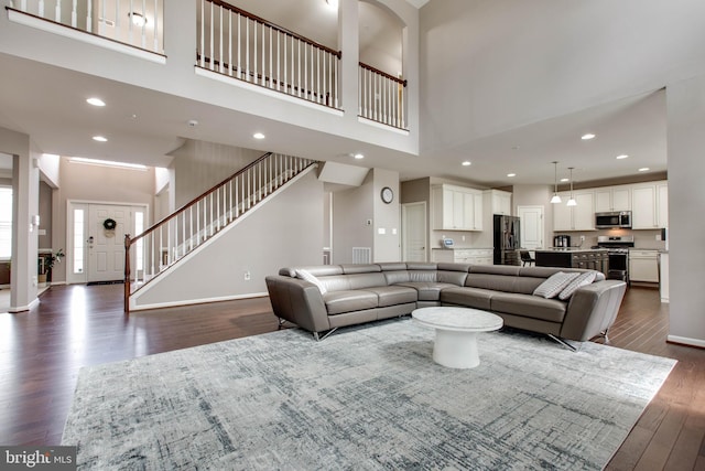 living area with stairway, baseboards, dark wood-type flooring, and recessed lighting