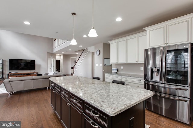 kitchen featuring dark wood-style flooring, decorative light fixtures, open floor plan, white cabinets, and stainless steel fridge