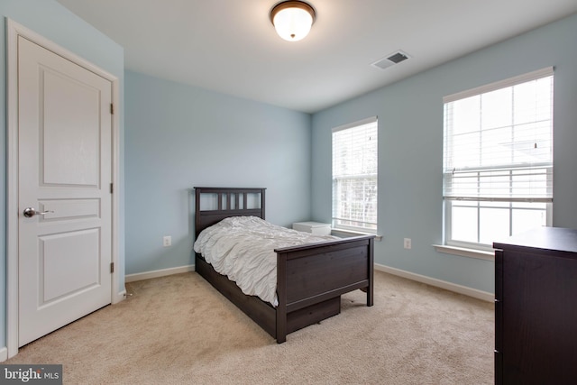 carpeted bedroom featuring visible vents, baseboards, and multiple windows