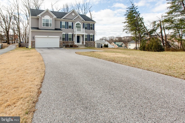 view of front of property with aphalt driveway, an attached garage, a balcony, stone siding, and a front yard