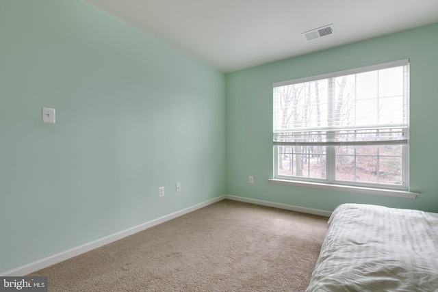 carpeted bedroom with multiple windows, visible vents, and baseboards