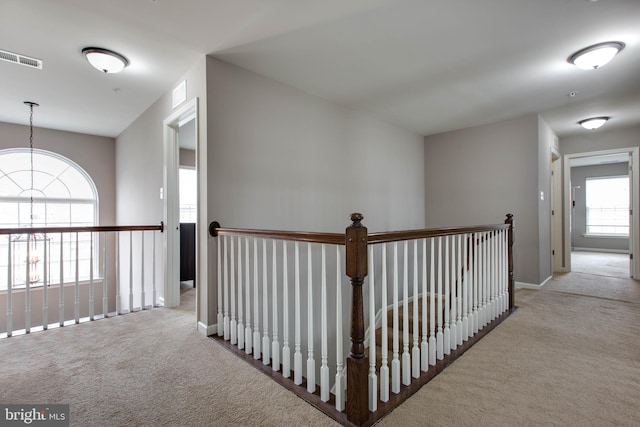 hall featuring carpet, visible vents, and baseboards