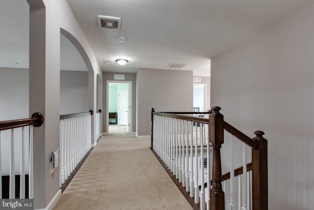 corridor with light colored carpet, baseboards, visible vents, and an upstairs landing