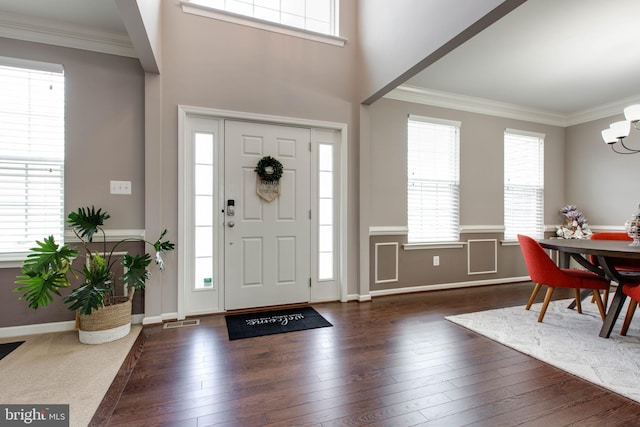 foyer entrance featuring visible vents, ornamental molding, hardwood / wood-style flooring, and a notable chandelier