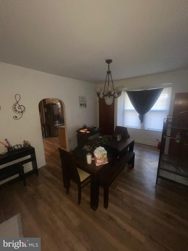 dining room featuring arched walkways and wood finished floors