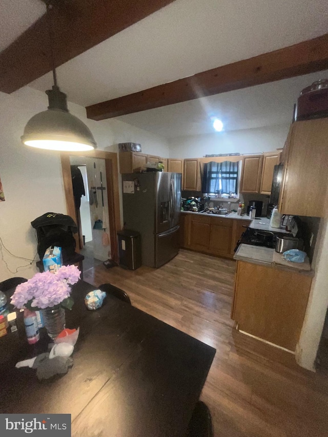 kitchen featuring light countertops, wood finished floors, beam ceiling, and stainless steel fridge with ice dispenser