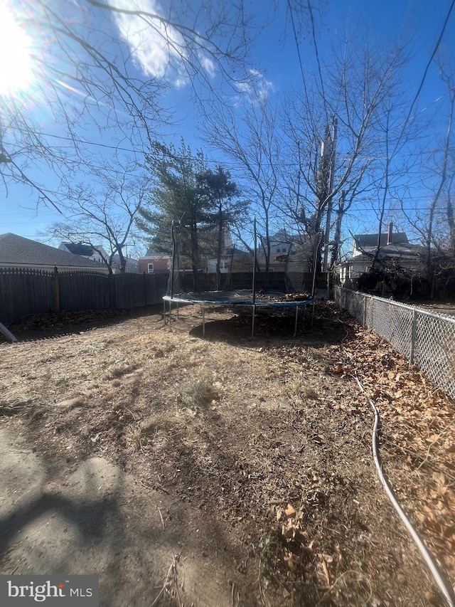 view of yard featuring a trampoline and a fenced backyard