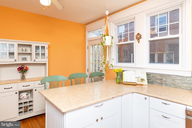 kitchen featuring open shelves, white cabinets, a peninsula, and glass insert cabinets