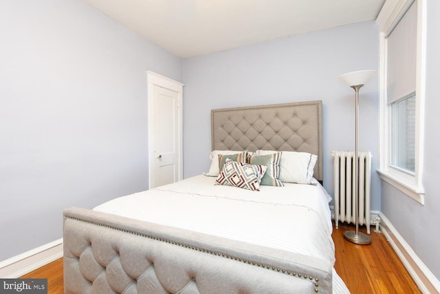 bedroom with radiator, baseboards, and wood finished floors