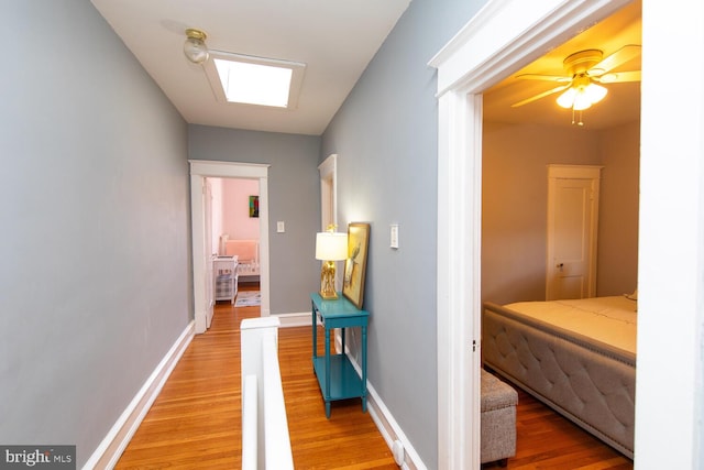 hallway featuring baseboards and light wood-style flooring