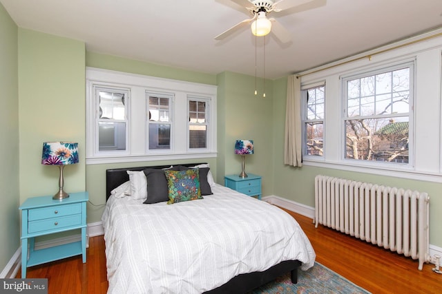 bedroom with ceiling fan, baseboards, wood finished floors, and radiator heating unit