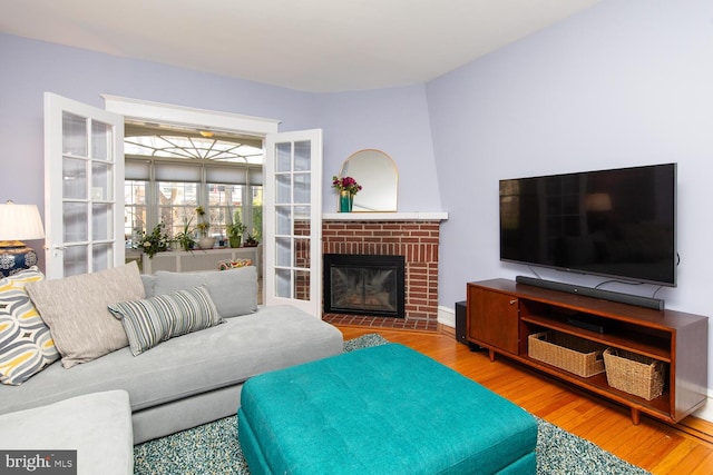 living room featuring a brick fireplace and wood finished floors