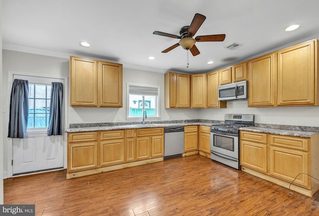 kitchen featuring visible vents, appliances with stainless steel finishes, ornamental molding, a sink, and wood finished floors