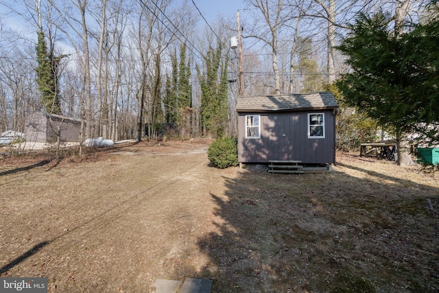 exterior space featuring a storage shed, a shingled roof, and an outdoor structure