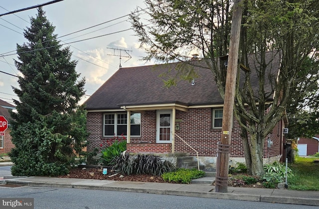 cape cod house with brick siding and a shingled roof