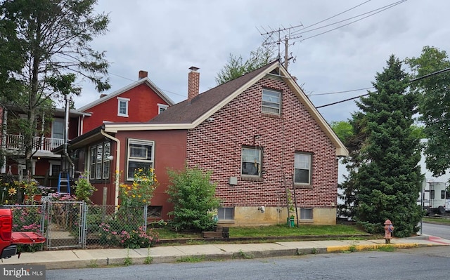 view of property exterior featuring brick siding, a chimney, and fence