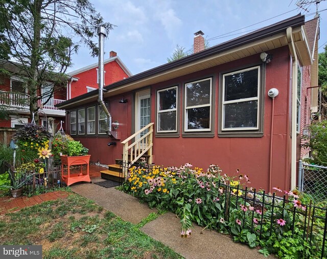 back of house featuring entry steps, a chimney, and fence