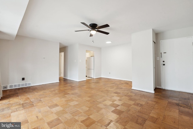 unfurnished room with ceiling fan, visible vents, and baseboards