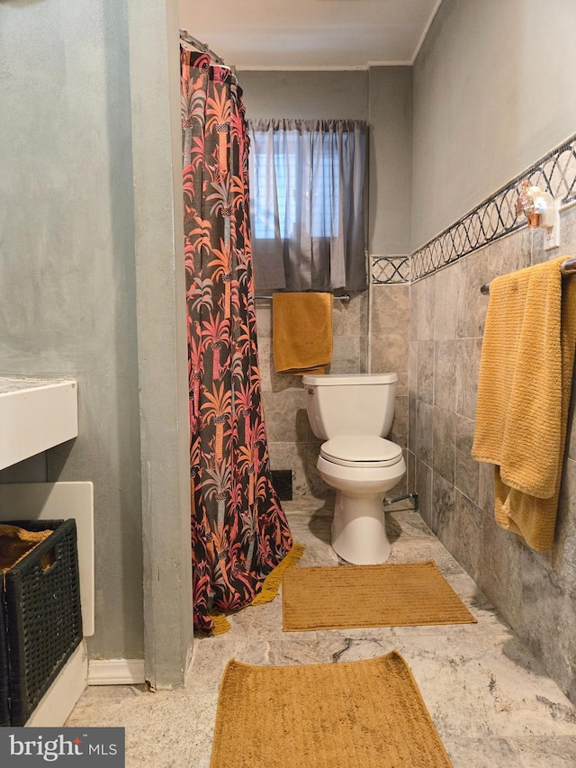 bathroom featuring tile walls, toilet, and a shower with curtain