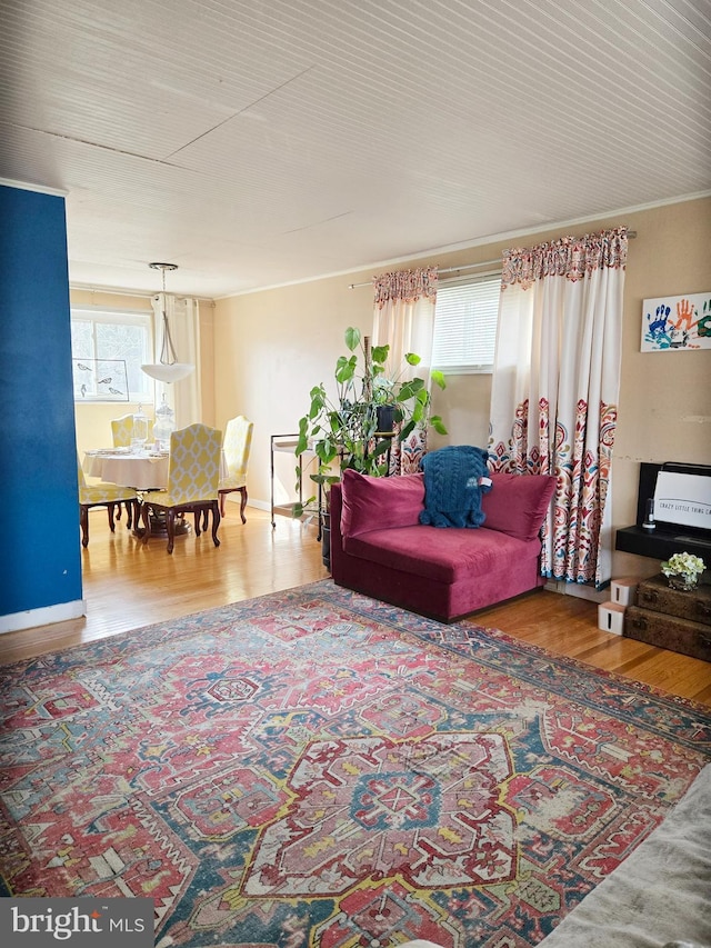 living room with crown molding, baseboards, and wood finished floors