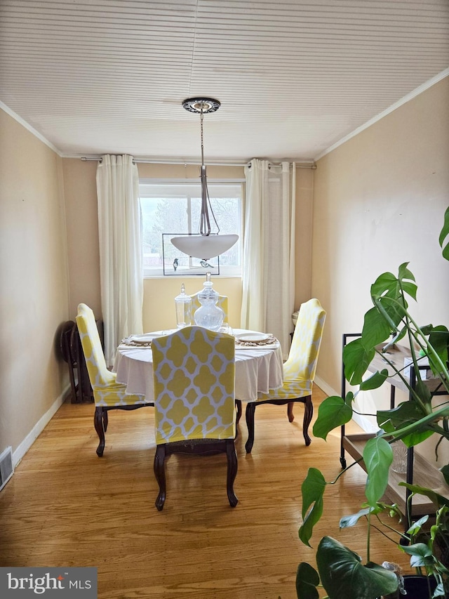 dining room with ornamental molding, light wood-style flooring, and baseboards