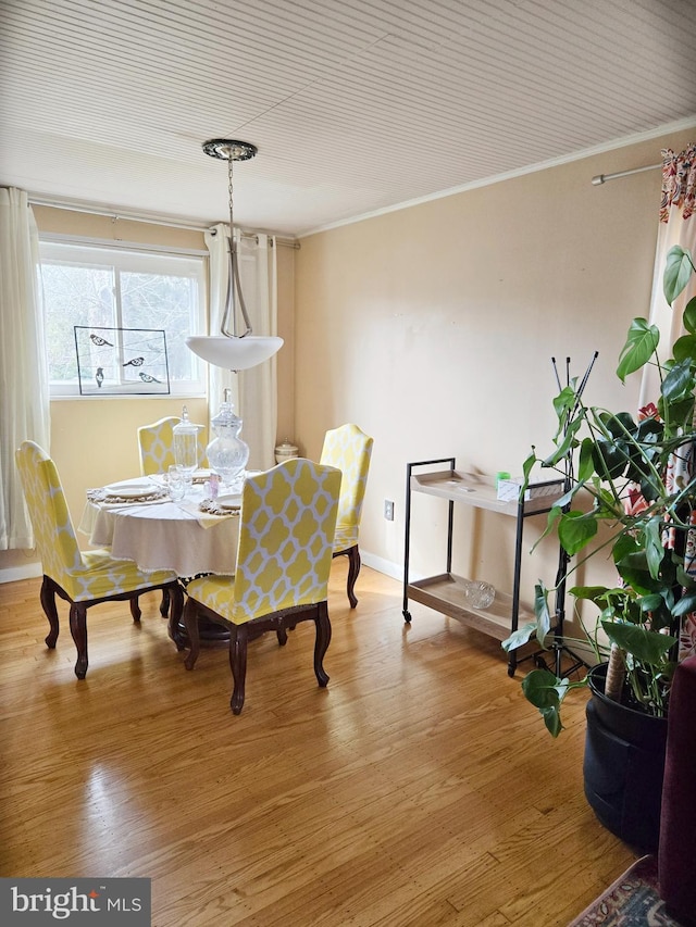 dining room featuring crown molding, baseboards, and wood finished floors