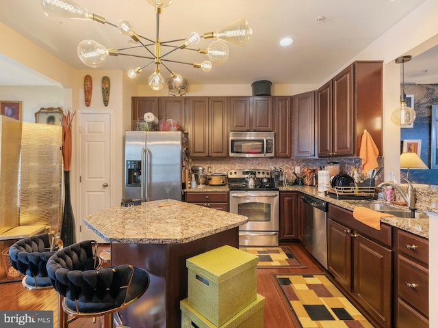 kitchen featuring decorative backsplash, stainless steel appliances, wood finished floors, and a sink