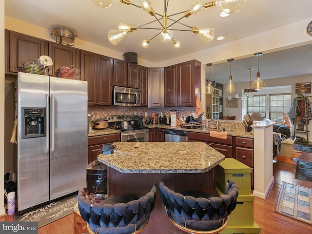 kitchen with light wood-type flooring, stainless steel appliances, light stone countertops, and tasteful backsplash