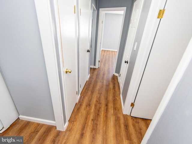 corridor with baseboards and wood finished floors