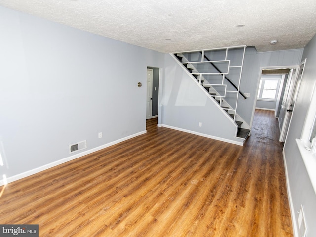 interior space with stairway, a textured ceiling, visible vents, and wood finished floors