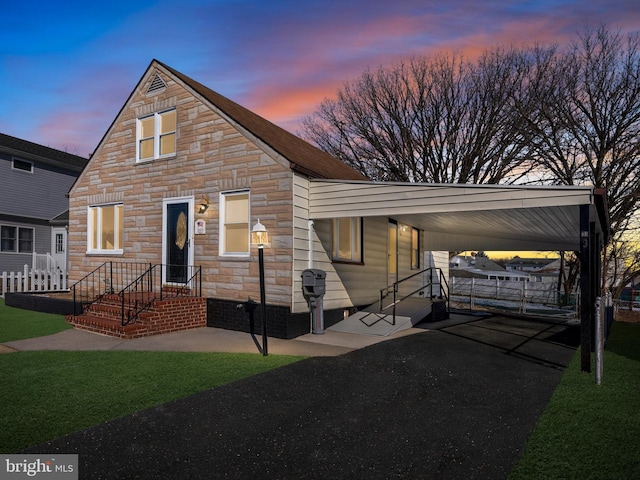 view of front of property featuring a yard, stone siding, an attached carport, and driveway