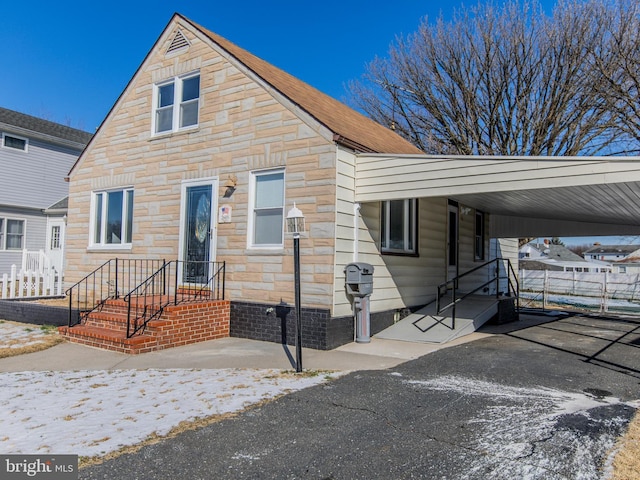 view of front of house featuring a carport, stone siding, and driveway