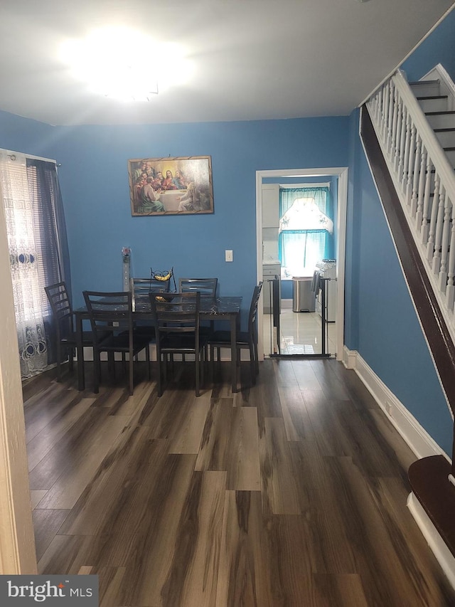 dining room featuring dark wood finished floors, baseboards, and stairs