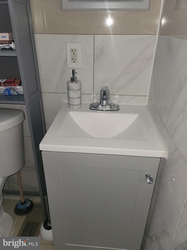 half bathroom featuring tile walls, vanity, and toilet