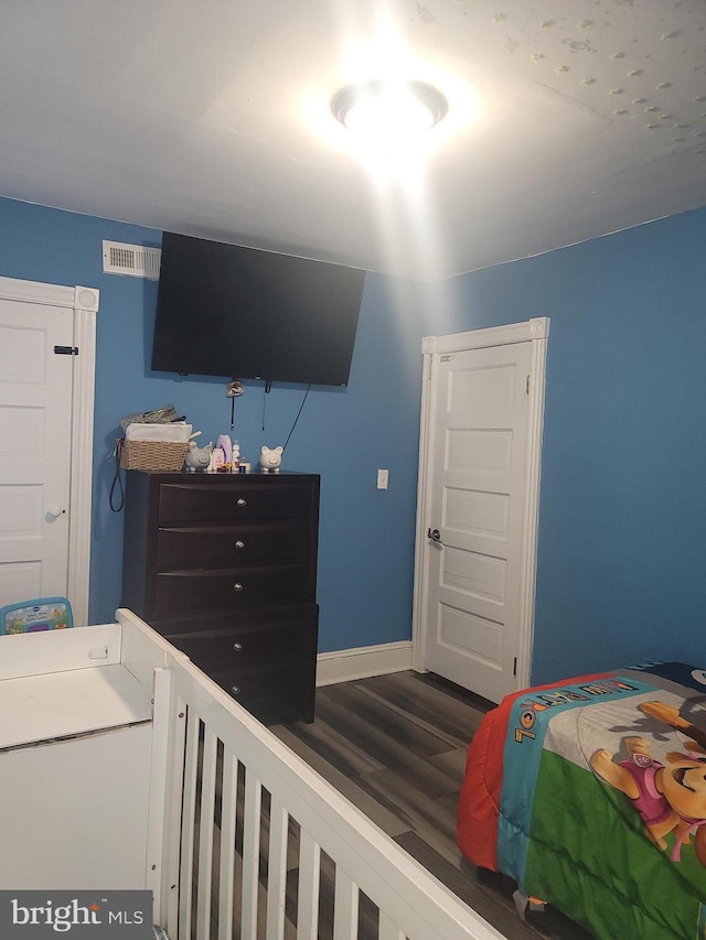 bedroom with wood finished floors, visible vents, and baseboards