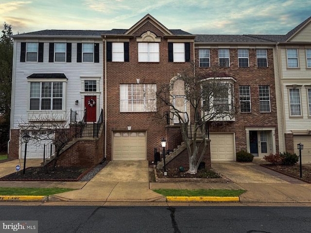 view of property with brick siding, concrete driveway, and stairs