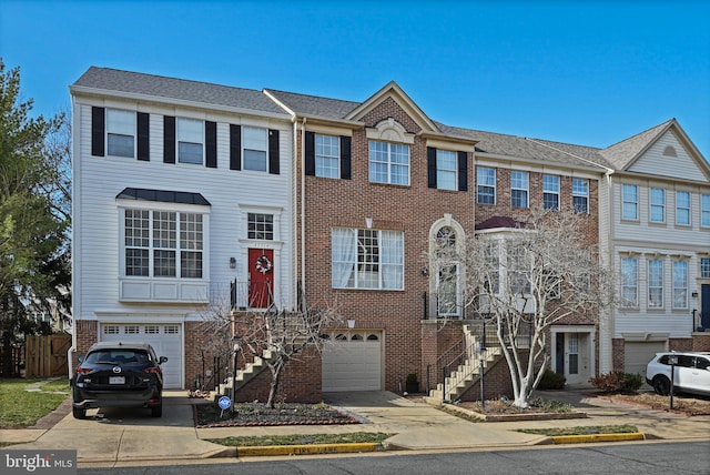 townhome / multi-family property featuring brick siding, stairway, an attached garage, and concrete driveway