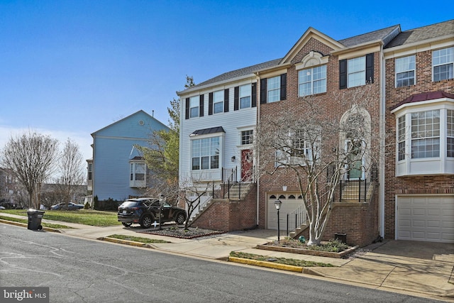 multi unit property with a garage, brick siding, and concrete driveway