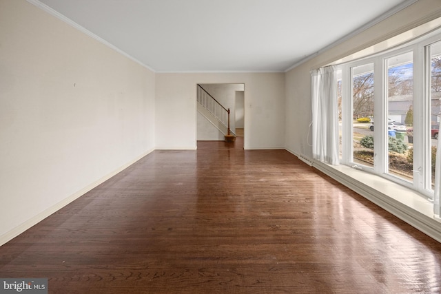 empty room with dark wood-type flooring, crown molding, baseboards, and stairs