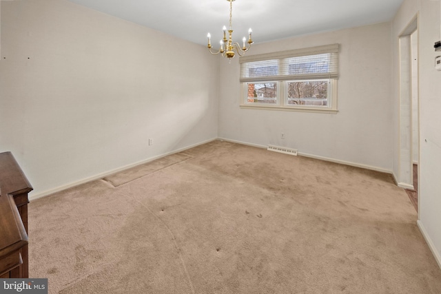 spare room with a chandelier, carpet floors, visible vents, and baseboards