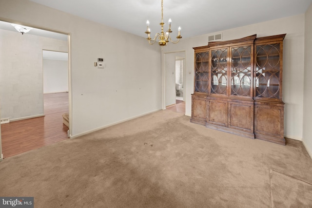 unfurnished dining area with a chandelier, carpet, visible vents, and baseboards