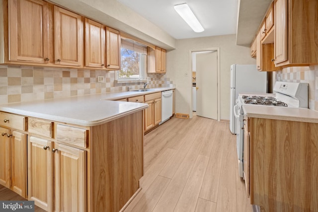 kitchen with light countertops, white appliances, a sink, and light wood-style floors