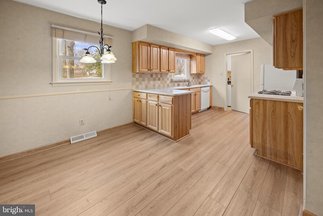 kitchen with white appliances, light wood finished floors, visible vents, a peninsula, and backsplash